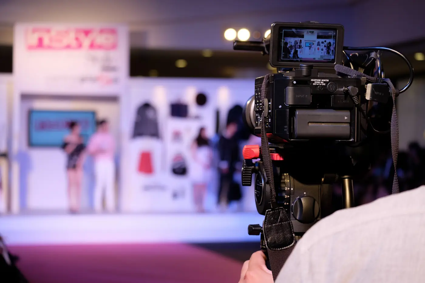 Professional video camera on a tripod filming a stage