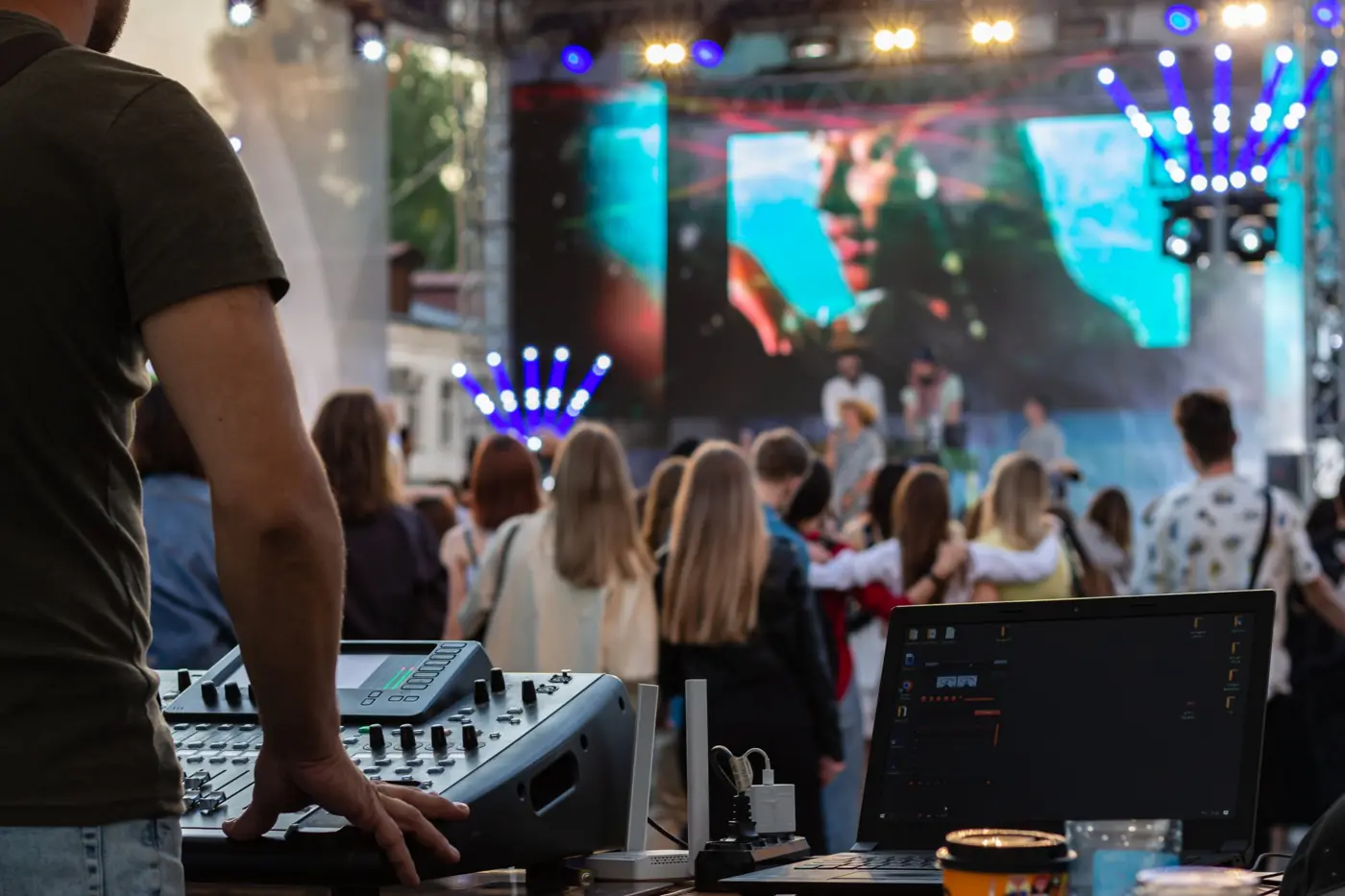 Sound engineer at a mixer facing an outdoor festival crowd